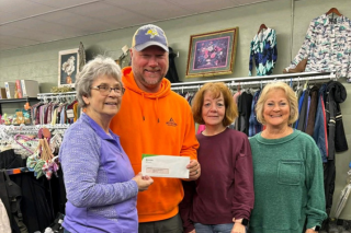 Four individuals hold check donation