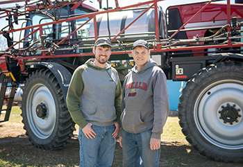 Matthew and Scott Sperry stand next to red sprayer