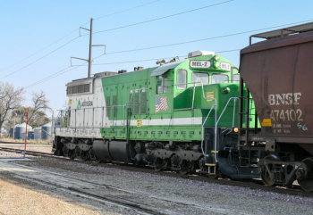 A green locomotive moves railcars