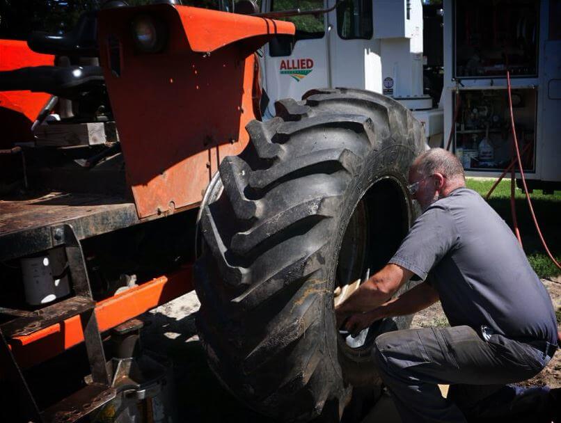 Gentleman fixing tractor tire at our Allied Cooperative Mauston Tire Shop.