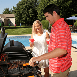 Man and woman grilling beside a pool