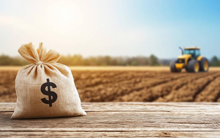 bag of money by field with tractor