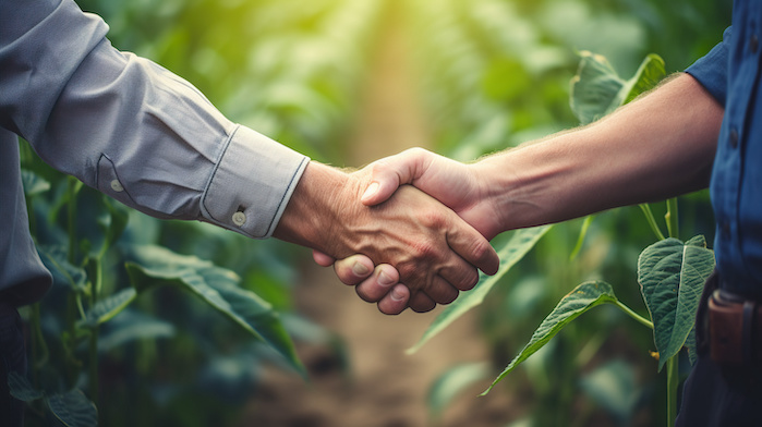 Grower and finance person shaking hands in field