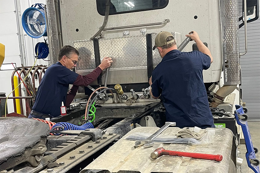 Two mechanics fixing a hydraulic system