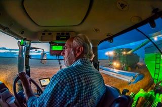 Farmer in cab of tractor with hi tech instruments in cab.