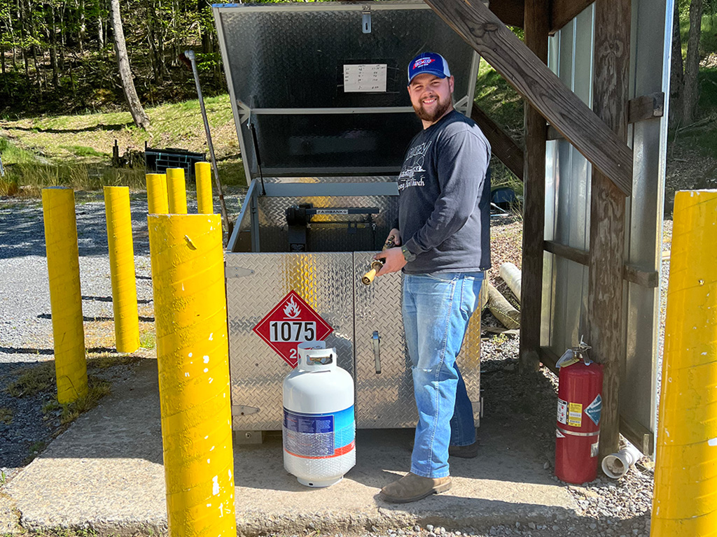 A worker standing at the propane tank refil station.