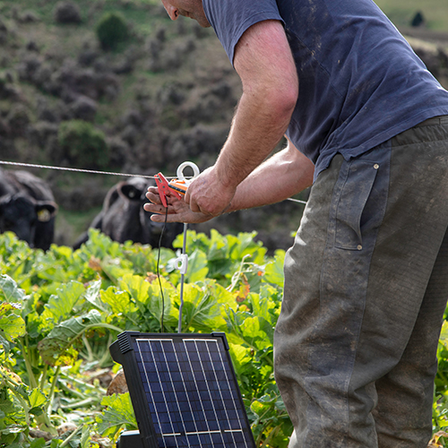 A man setting up a Gallagher fence energizer.