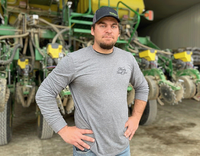 Heritage Employee Standing In Front of Large Piece of Farm Machinery