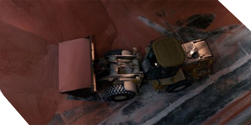 Arial View of Excavator Moving Fertilizer in a Warehouse