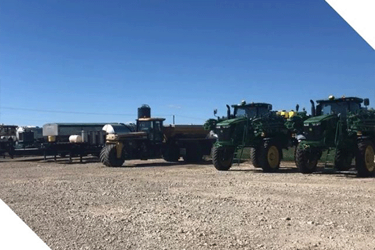 Farm Machinery Lined Up In A Gravel Lot