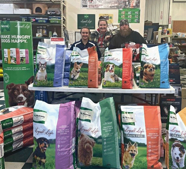 Heritage Country Store Employees Standing Beside a Pet Food Display