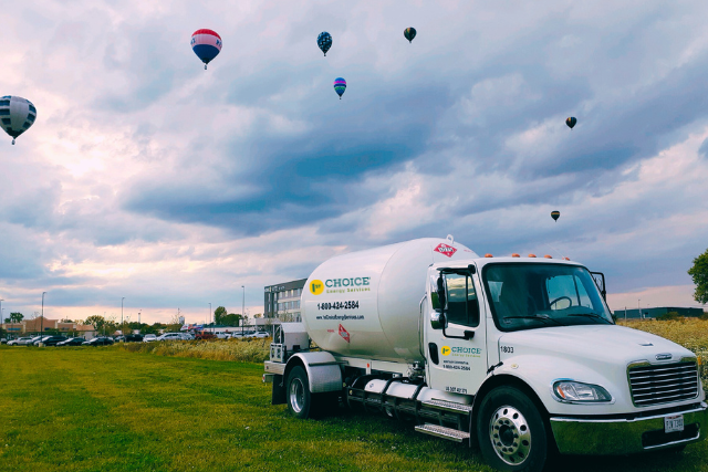 Propane Truck Sitting Below Hot Air Balloons in the Sky