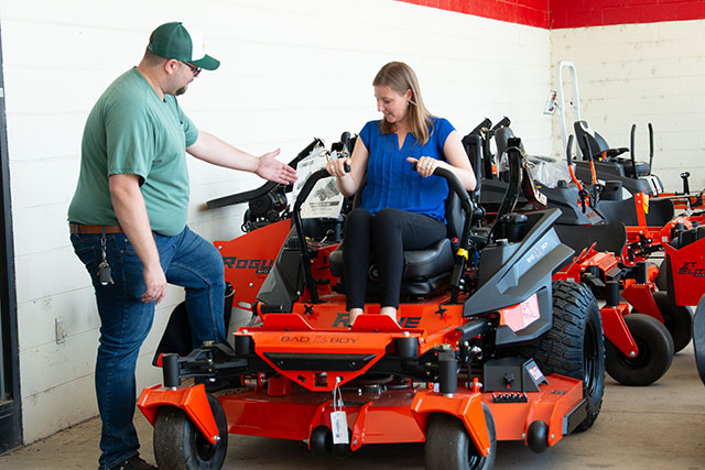 An employee demonstrating a Bad Boy mower to a customer.