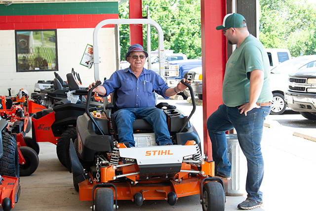 An employee demonstrating a Stihl mower to a customer.