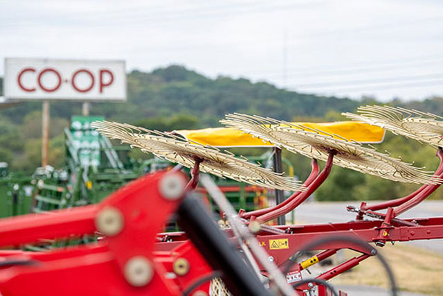 An upclose shot of a hay spreader with CO-OP in the background.