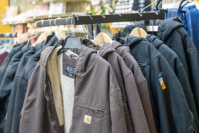 A clothing rack filled with Carhartt zip up jackets.