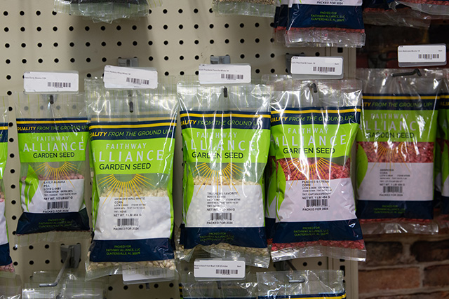 Faithway Alliance garden seed bags hanging from a display wall.