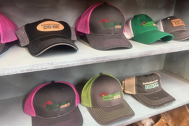 Shelves lined with various colors of trucker hats all with the Southeastern Farmers Co-op logo on them.