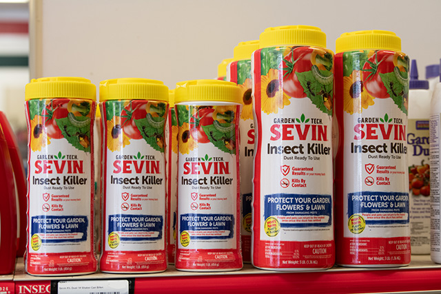 Two different sized bottles of Sevin Insect Killer line a shelf.