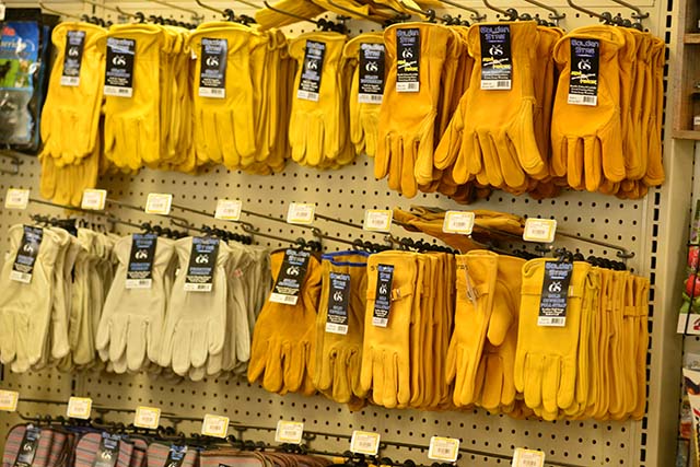 A wall rack lined with various yellow working gloves.