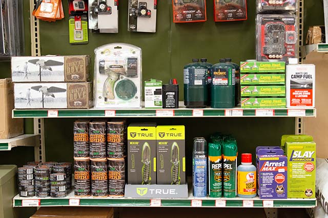 Shelves of hunting equipment such as knives, bug spray, cameras, and more.