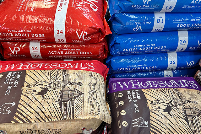 Wholesomes and Valu Pak dog food bags stacked on a pallet