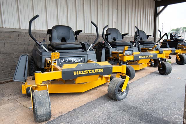 A line up of Hustler Raptor mowers in front of a building.