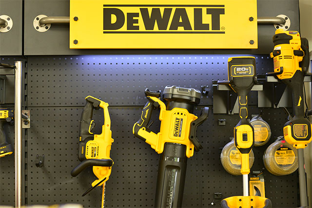 A lit up wall display with various DeWalt power equipment hanging on it.