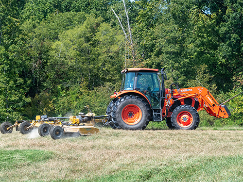 A tractor pulling a cutter through a field