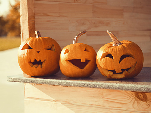 Three jack-o-lanters sitting on a shelf.