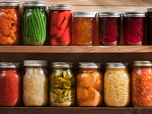 Various canned goods lined up on wooden shelves.