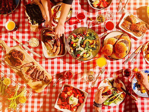 A picnic table covered in an assortment of food.