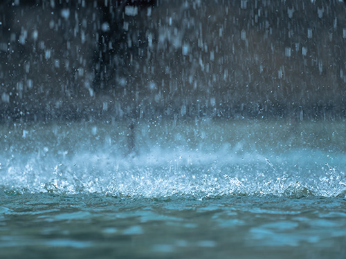 Rain falling from the sky into a puddle.