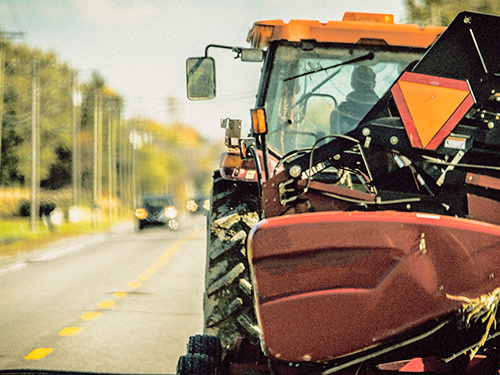 A tractor driving down a busy street