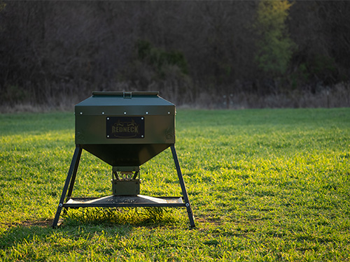 A Redneck broadcast deer feeder out in a field at dusk