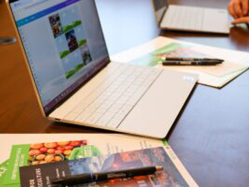 A laptop sitting on a desk covered in papers.