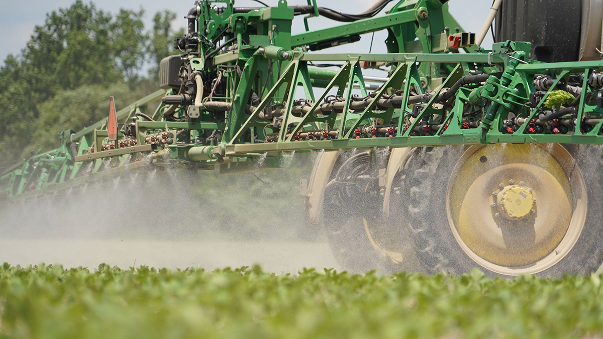 a tractor pulling a sprayer spraying crops in a field