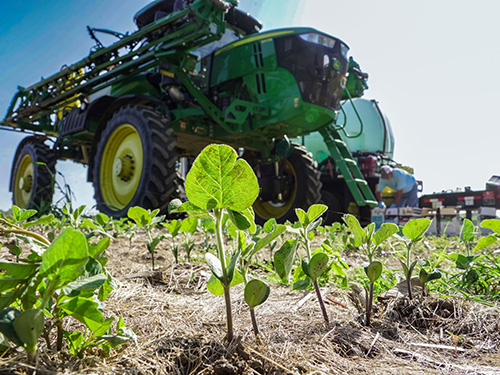 A farmer in the field setting up his tractor sprayer