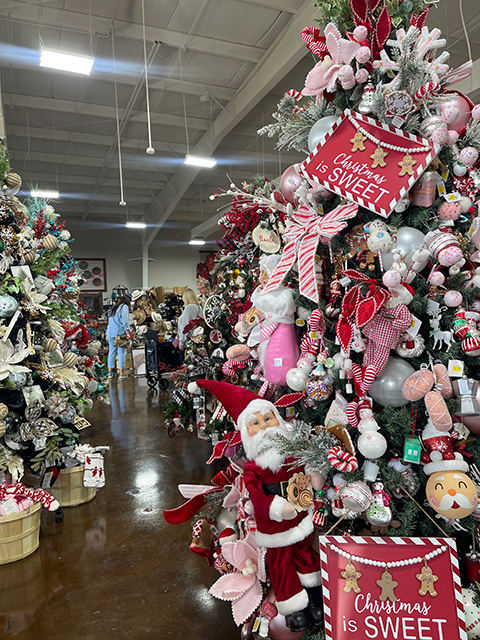 Christmas trees cluttered with decorations and ornaments line the aisle.