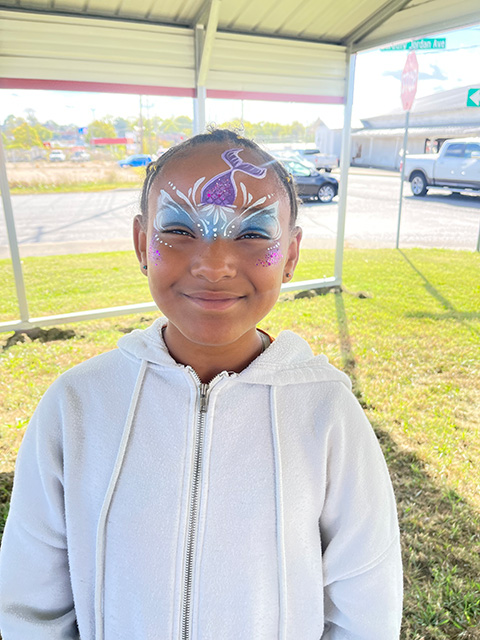 A girl with mermaid face paint on.