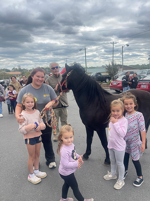 A family taking a photo next to a pony.